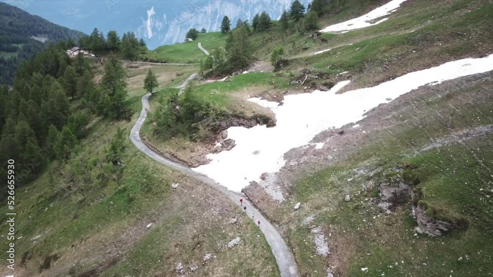 Aerial view: swiss alps valley, meadows with grass, some snow from winter melting with the warmer temperatures, drone push in Aerial view: swiss alps valley, meadows with grass, some snow from winter melting with the warmer temperatures, drone push in