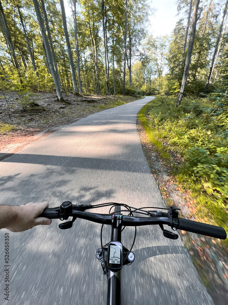 Close up of bicycle handle bar. First-person view of bicycle riding. Man riding a bike. Holding bike handlebar with one hand. Summertime outdoor leisure sport activity. Close up of bicycle handle bar. First-person view of bicycle riding. Man riding a bike. Holding bike handlebar with one hand. Summertime outdoor leisure sport activity.