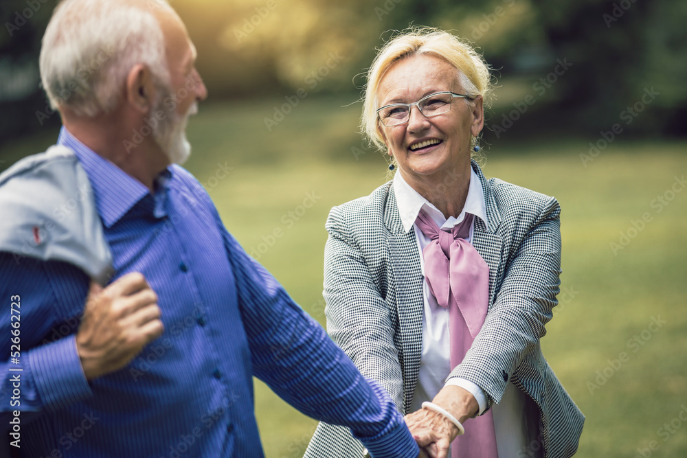 Senior active caucasian couple holding hands looks happy in the park in the afternoon Senior active caucasian couple holding hands looks happy in the park in the afternoon