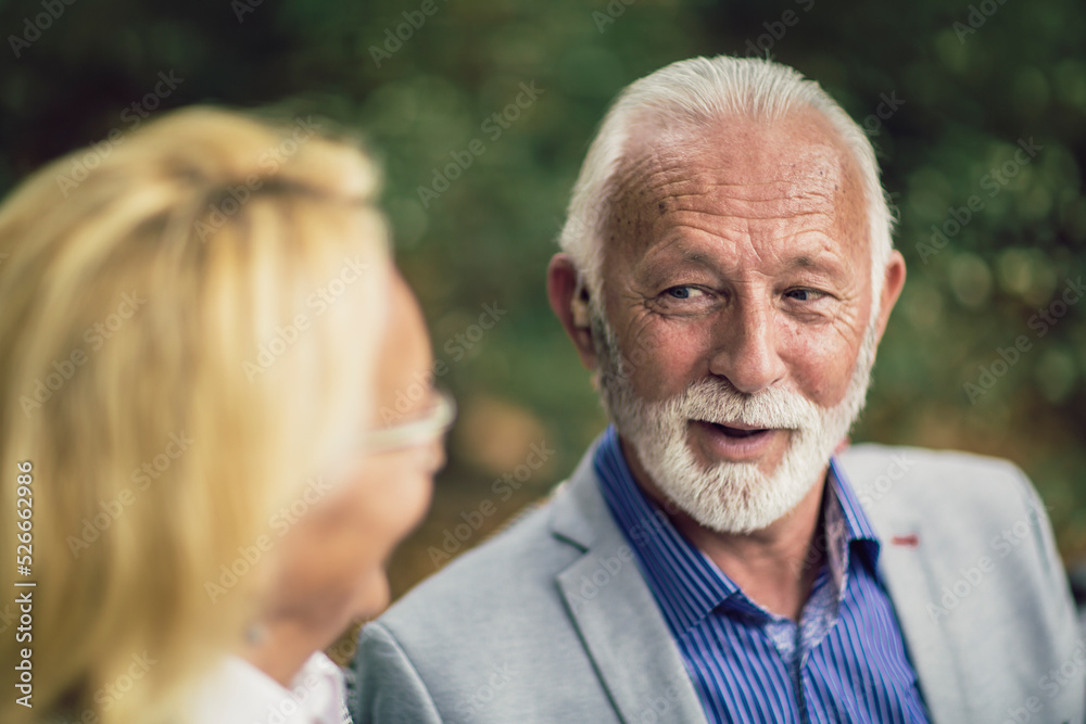 Senior couple with a hearing problem sitting on bench outdoor