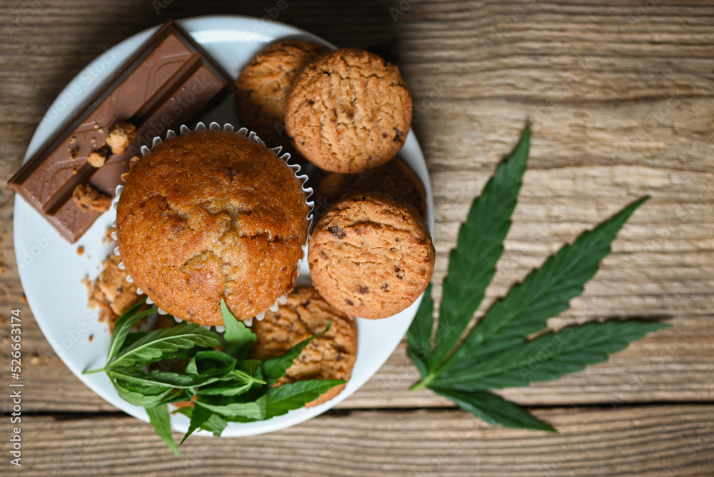 Cannabis food cookies with cake chocolate cannabis leaf marijuana herb on wooden and dark background, delicious sweet dessert cookie with hemp leaf plant THC CBD herbs food snack and medical Cannabis food cookies with cake chocolate cannabis leaf marijuana herb on wooden and dark background, delicious sweet dessert cookie with hemp leaf plant THC CBD herbs food snack and medical
