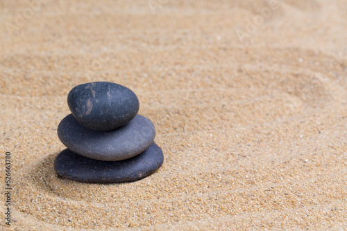 Black spa stone on the sea sand with copy space. Concept for harmony spirituality and spirituality. zen stones and buddhism Balance relaxation meditation for life.
