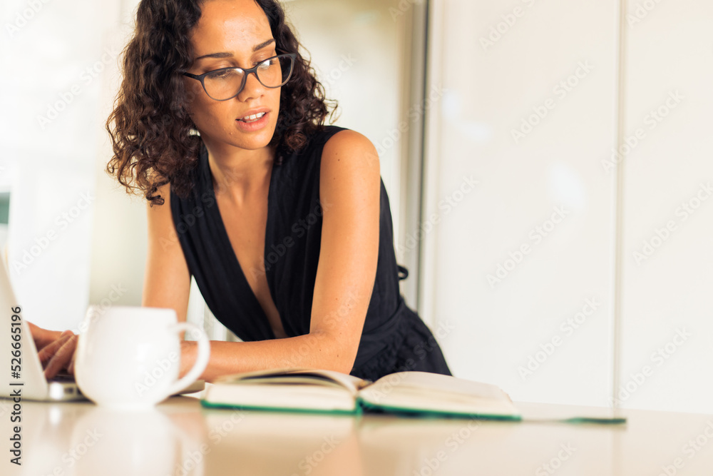 Obraz premium Focused freelancer looking in diary and using laptop in kitchen