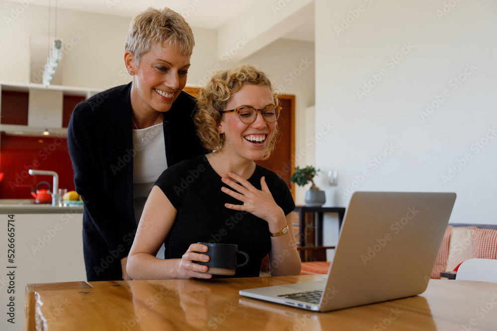 Happy daughter and mother video calling over laptop at home