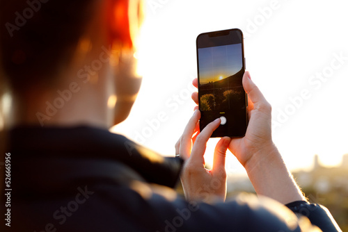 Woman photographing mountain during sunrise with phone