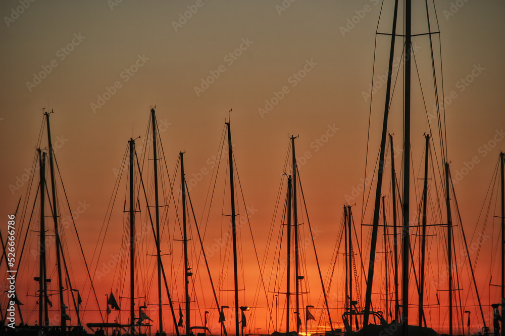Yacht masts and rigging in silhouette at sunset