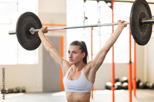 Focused sportswoman with barbell over head