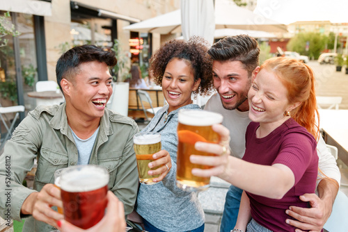 Cheerful multiethnic friends enjoying beer in outdoor cafe