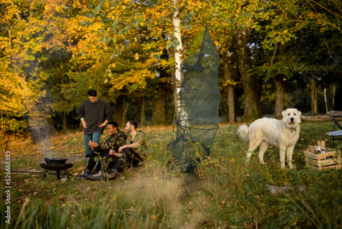 Multiracial male friends having a picnic and fishing on river or lake coast. Concept of leisure and weekend in nature. Idea of friendship and enjoying time together. Autumn day © rh2010