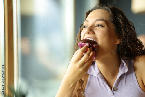 Foto Woman eating chocolate cupcake in a restaurant