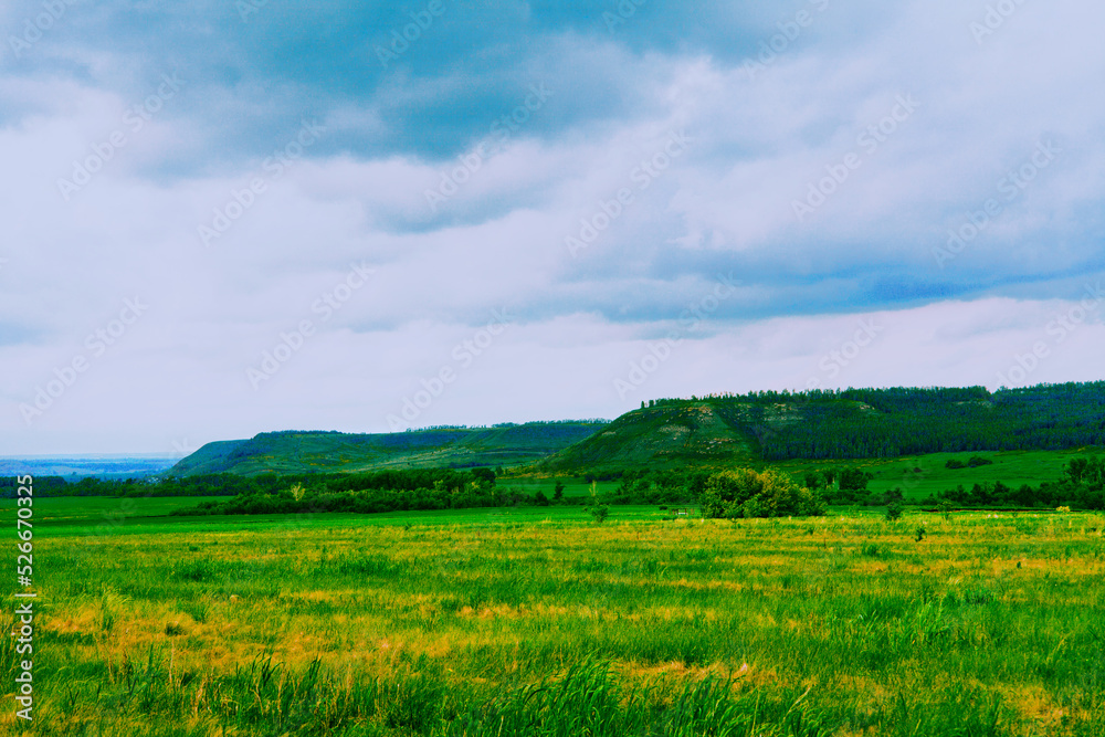 Beautiful landscape on a sunny day. An earthen road. A landscape with a colorful sky under the sun. Mountain slope. Green trees.against the background of a green forest clearing.summer meadow Beautiful landscape on a sunny day. An earthen road. A landscape with a colorful sky under the sun. Mountain slope. Green trees.against the background of a green forest clearing.summer meadow
