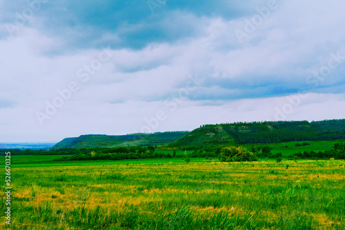 Beautiful landscape on a sunny day. An earthen road. A landscape with a colorful sky under the sun. Mountain slope. Green trees.against the background of a green forest clearing.summer meadow