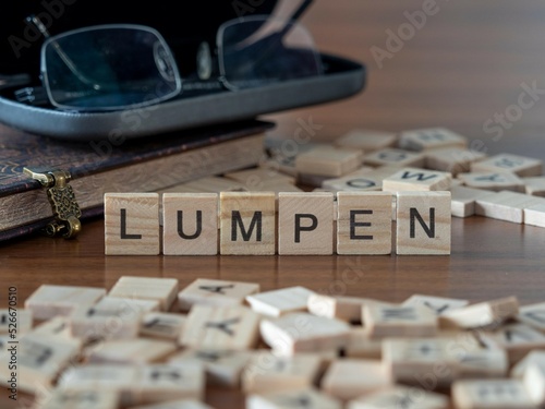 lumpen Wort oder Konzept dargestellt durch hölzerne Buchstabenfliesen auf einem Holztisch mit Brille und einem Buch photo