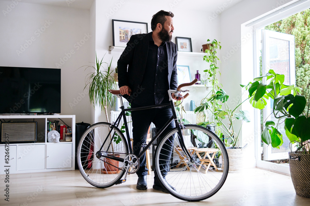 Businessman standing with bicycle in living room at home Businessman standing with bicycle in living room at home