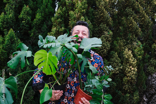 Cheerful man carrying potted plants at back yard