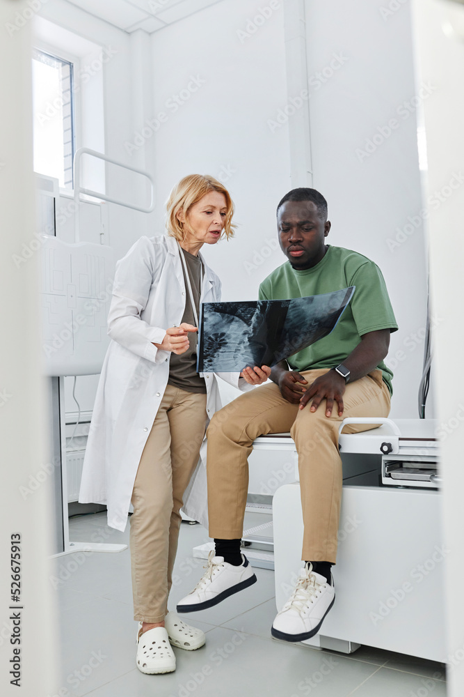 Doctor explaining X-ray to patient sitting in clinic Doctor explaining X-ray to patient sitting in clinic