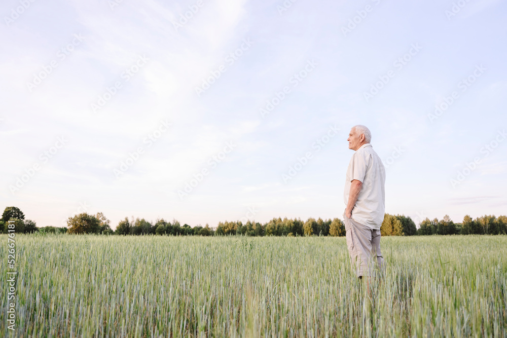 Farmer with hands in pockets standing on cornfield Farmer with hands in pockets standing on cornfield