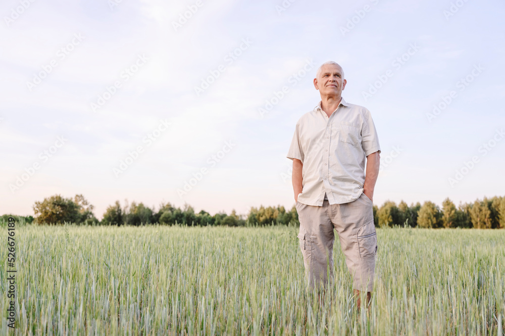 Senior farmer standing with hands in pockets at farm Senior farmer standing with hands in pockets at farm