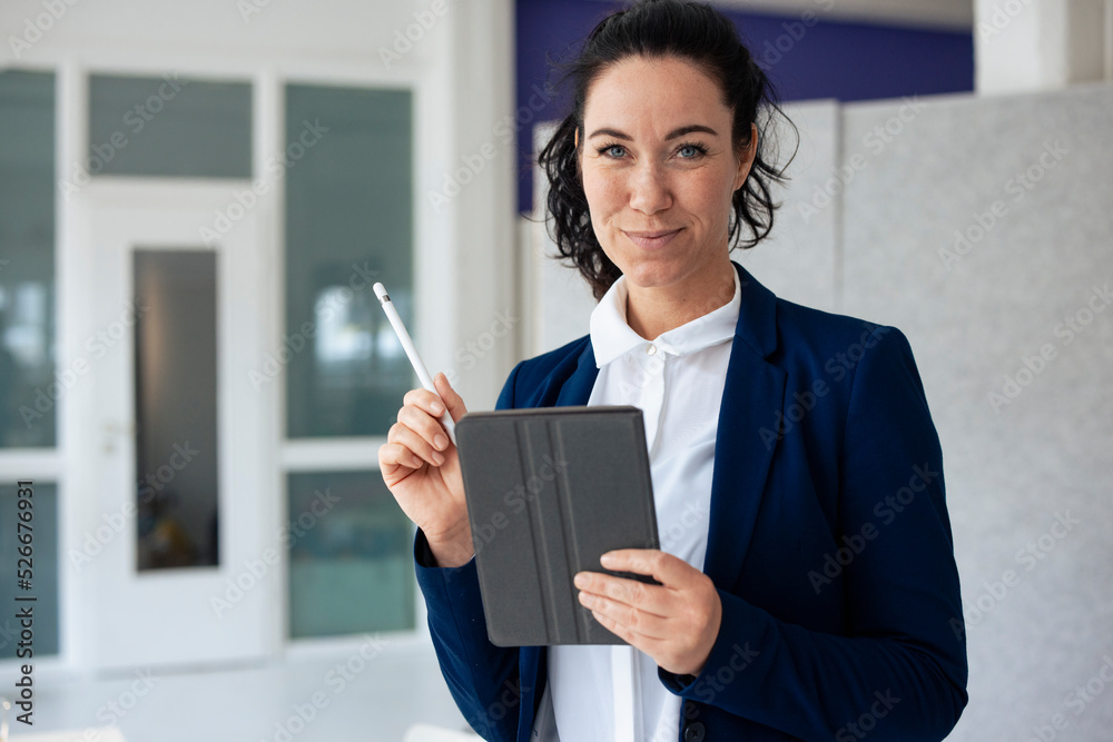 Smiling businesswoman holding digitized pen and tablet PC Smiling businesswoman holding digitized pen and tablet PC