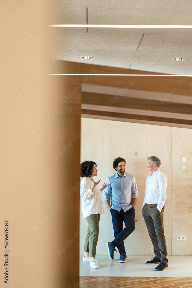 Happy business colleagues planning strategy in corridor