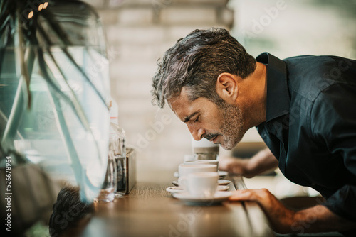 Mature man smelling coffee on table in cafe photo