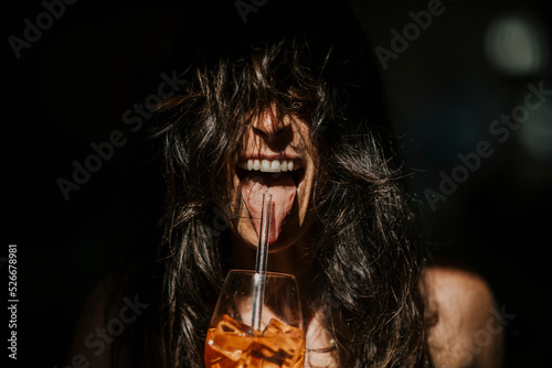 Happy woman with mouth open having drink with straw photo