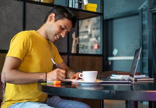 Cheerful Indian man smiling and making notes