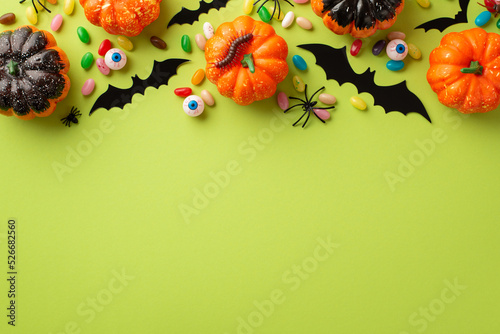 Halloween concept. Top view photo of pumpkins bat silhouettes spooky eyes spiders centipede and candies on isolated light green background with empty space