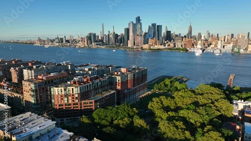 Midtown Manhattan skyline. Aerial pullback reveals Hoboken NJ. Summer golden hour light. photo