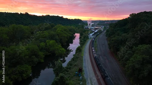 Tanker train cars on railroad track beside river during morning sunrise. Aerial view. photo