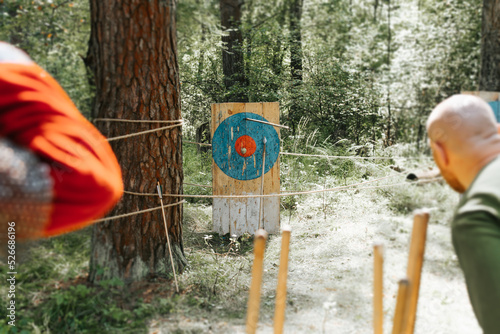 Close-up of medieval soldiers competing in marksmanship, throwing spear at target in open air. Selective focus on wooden shield.