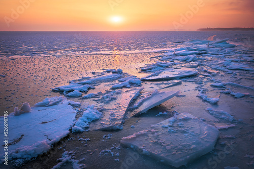 Sunrise and frozen sea. Beautiful winter landscape with lake and red sun in morning time. Daybreak