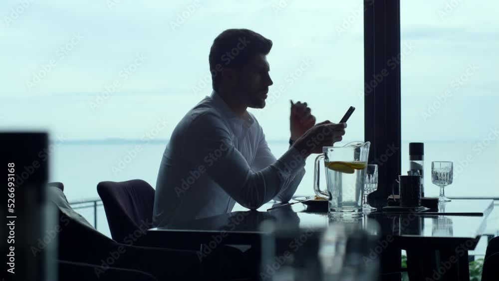 Busy businessman reading message on smartphone on lunch in luxury restaurant Busy businessman reading message on smartphone on lunch in luxury restaurant