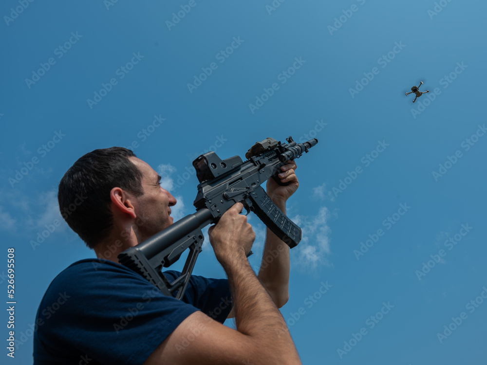 Caucasian man shoots a flying drone with a rifle. Caucasian man shoots a flying drone with a rifle.