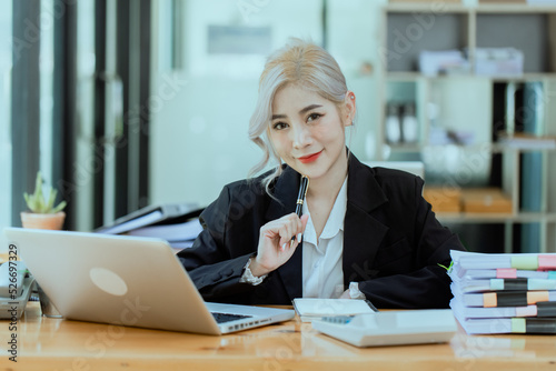 Happy smiling business woman Working on laptop computer with paperwork at desk in a modern office, business finance technology concept. 