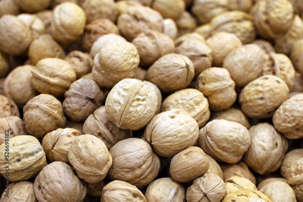 Walnuts heap for background. Dry nuts in shells on a market, protein food for brain health Walnuts heap for background. Dry nuts in shells on a market, protein food for brain health