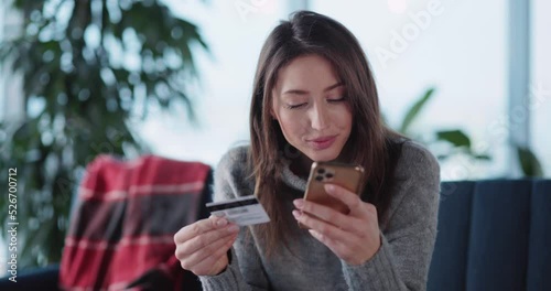 Young caucasian casual woman staying home in winter using smartphone paying for online food delivery service quickly and easily. Credit card payment. photo