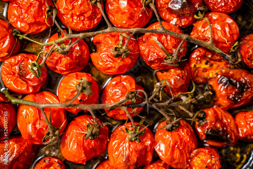 Close up shot of roasted red cherry tomatoes with garlic, herbs and olive