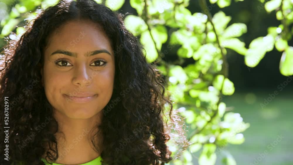 Beautiful mixed race African American girl biracial teenager young woman outside smiling and laughing standing under a tree Beautiful mixed race African American girl biracial teenager young woman outside smiling and laughing standing under a tree