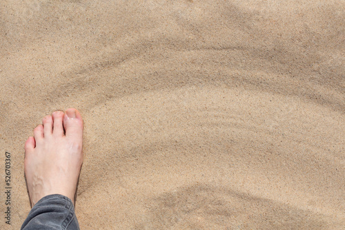 a woman's foot on the sand with a copy of the space