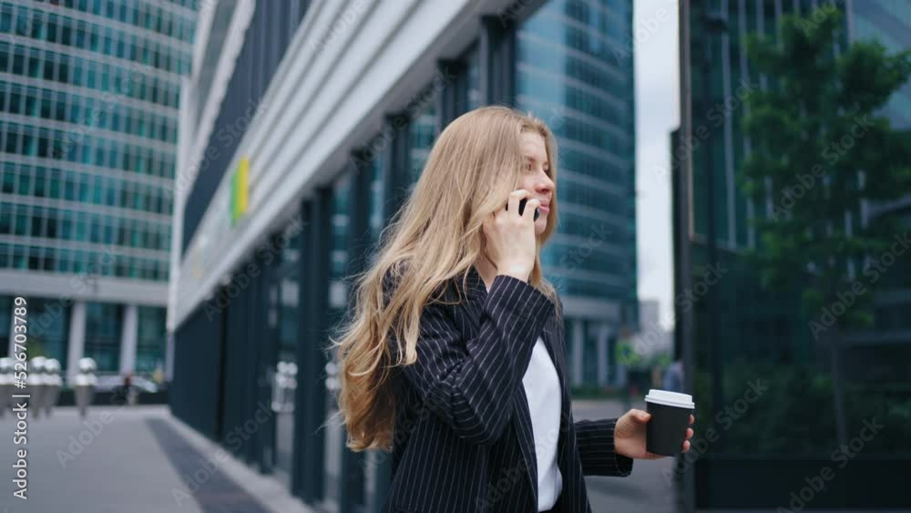 businesswoman is talking by cell phone while walking in city center in modern business district businesswoman is talking by cell phone while walking in city center in modern business district