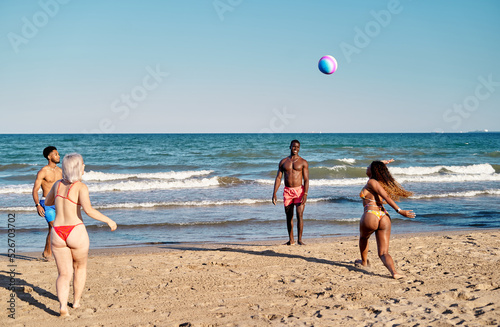 Diverse friends playing with beach ball