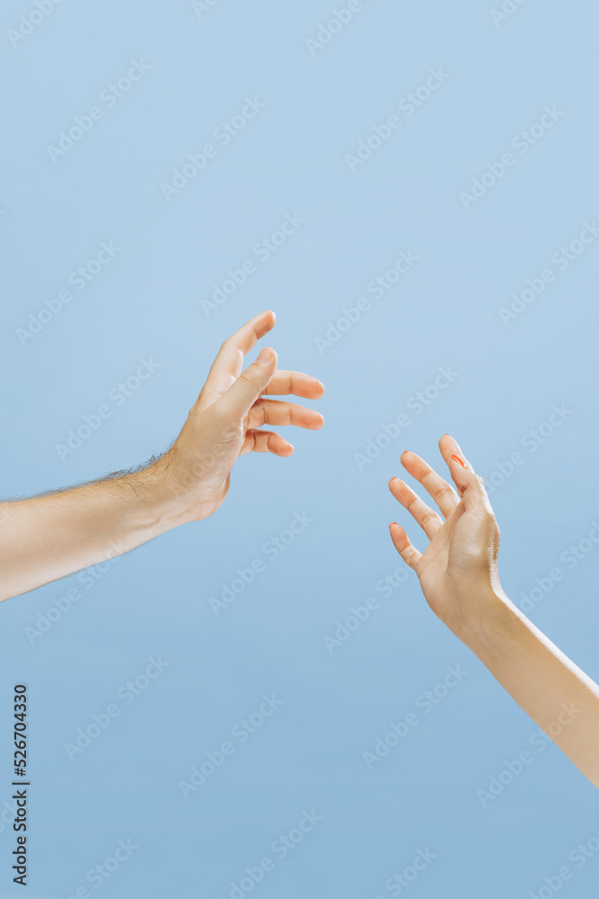 Male and female hands greeting each other isolated on blue background. Concept of relationship, feelings, community, care, support, symbolism, art Male and female hands greeting each other isolated on blue background. Concept of relationship, feelings, community, care, support, symbolism, art