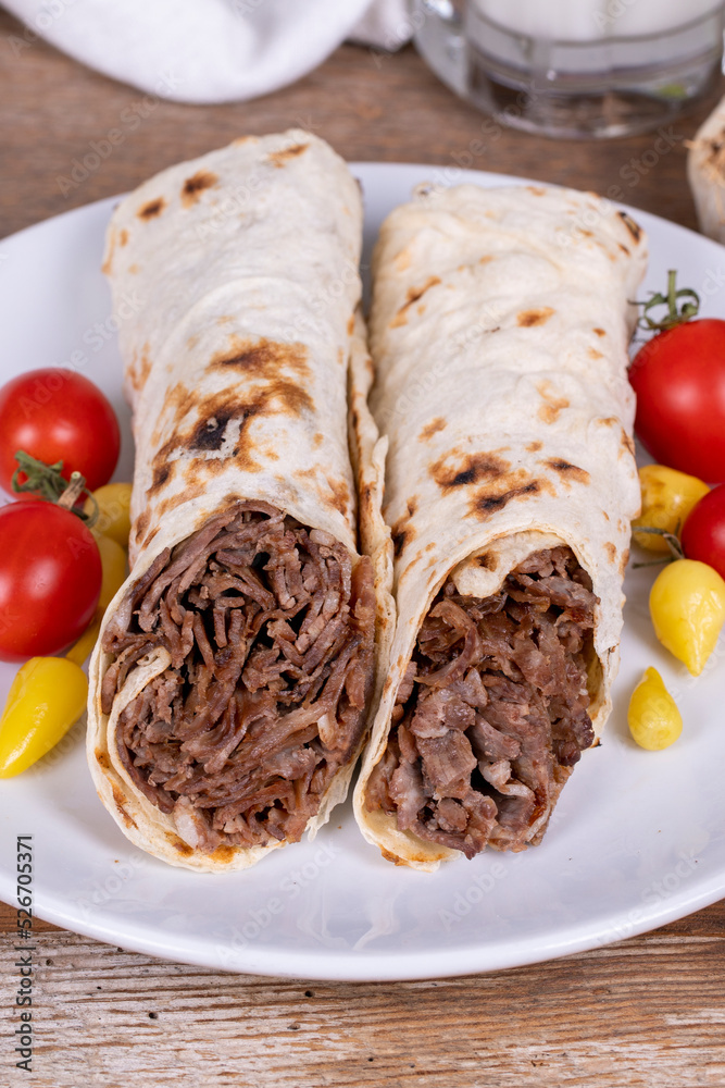 Wrap Doner Kebab. Meat doner kebab on wooden background. Traditional Turkish cuisine. Close-up. local name durum et doner Wrap Doner Kebab. Meat doner kebab on wooden background. Traditional Turkish cuisine. Close-up. local name durum et doner