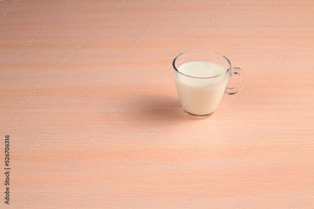 White Beverage in a Glass Cup on a Wooden Tabletop. Milk in a Transparent Mug on a Table. White Beverage in a Glass Cup on a Wooden Tabletop. Milk in a Transparent Mug on a Table.