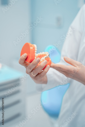 full dentures in orange color in the hands of a medical worker