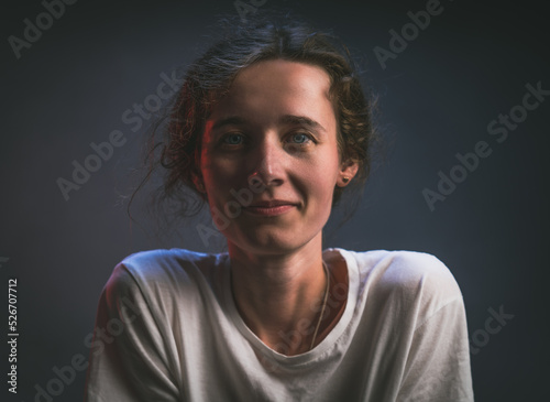 Young thin girl like a boy in a white t-shirt look straight smiling portrait on a gray background baby face girl looks like a boy tanned face
