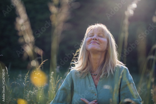 Fotografie Senior woman with face up meditating at park on summer day, mental health concept