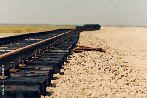 Laying of new railway tracks with wooden sleepers laid on groundwork crushed stone. Railway industry and transport infrastructure.