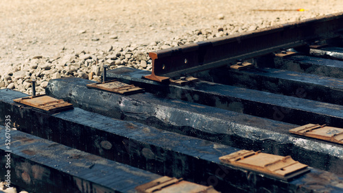 Laying of new railway tracks with wooden sleepers laid on groundwork crushed stone. Railway industry and transport infrastructure.